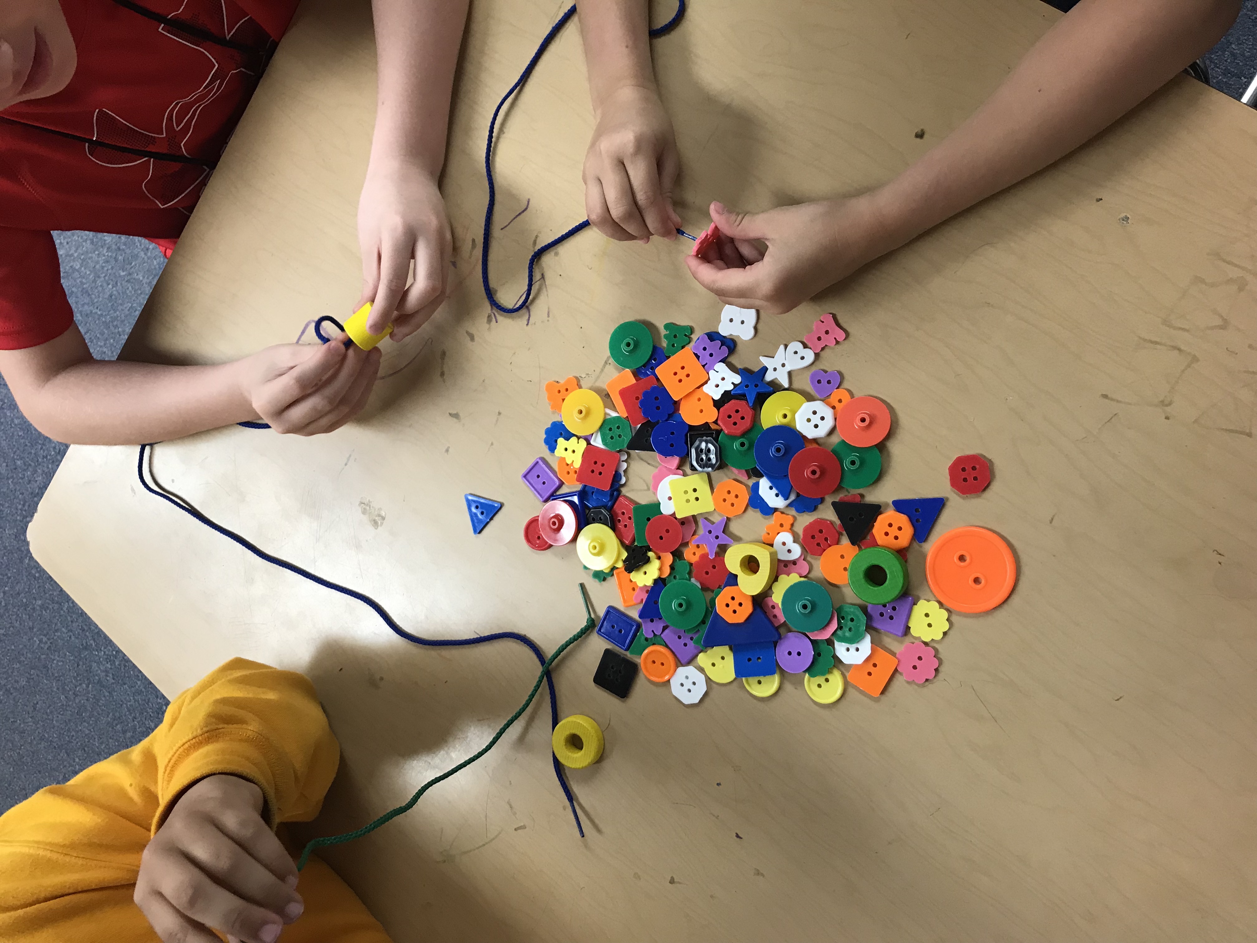 Kids playing with strings and buttons