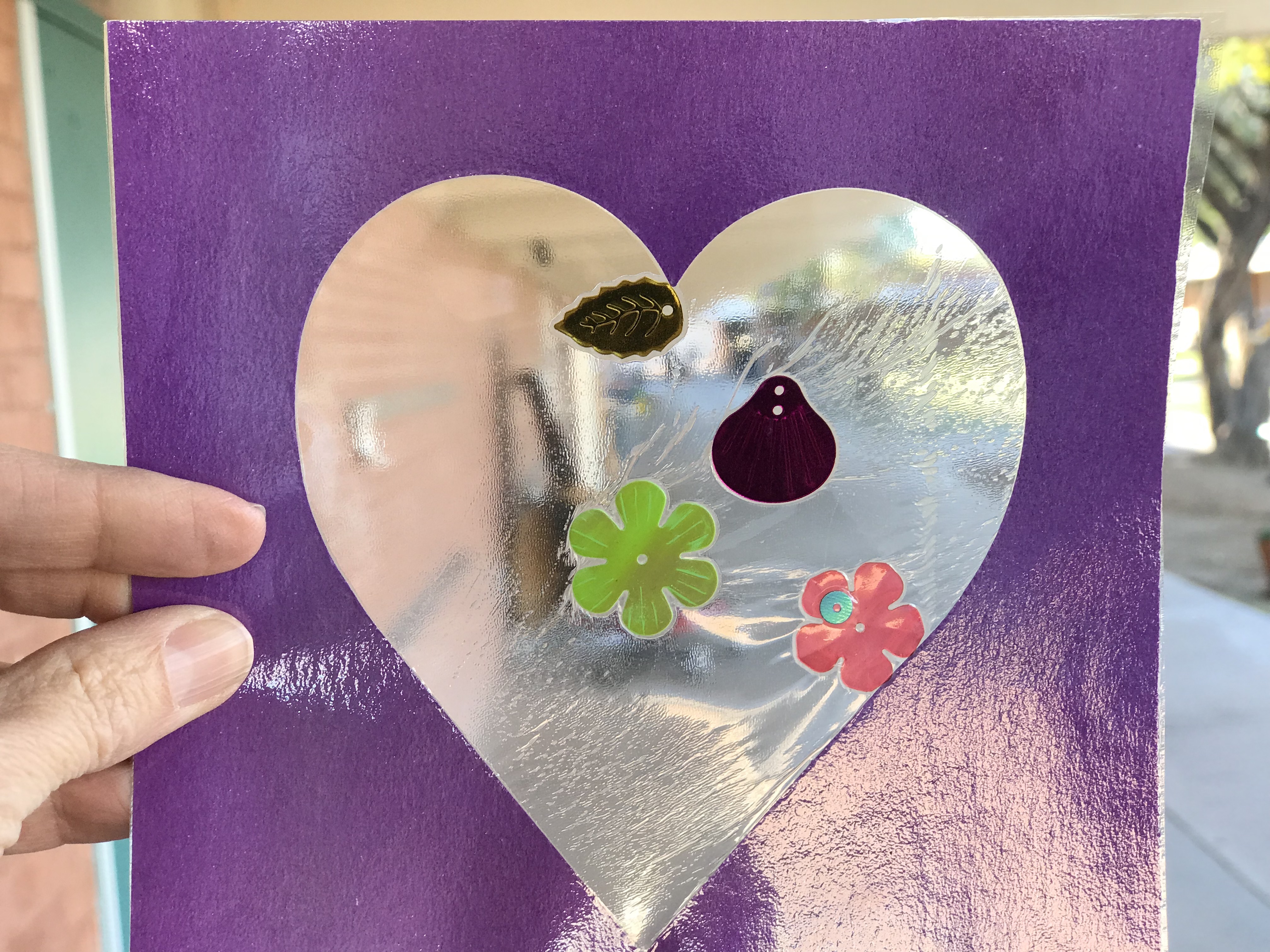 Laminated plastic sheet with purple heart outline containing flowers and leaves