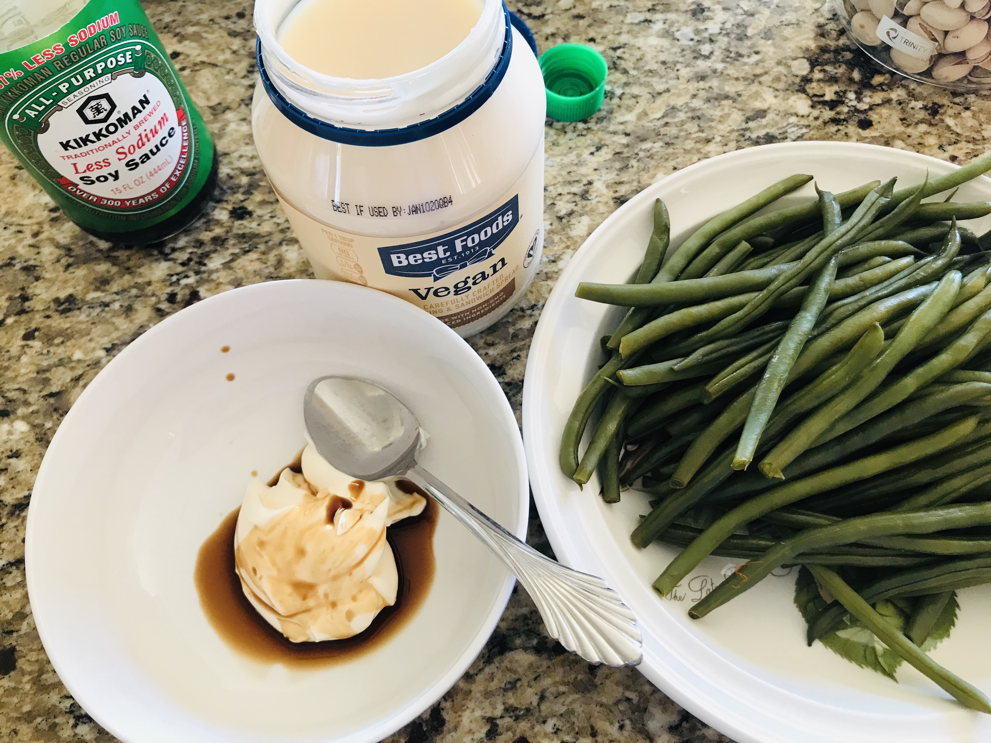 Bowl mixture of vegan mayonnaise and soy sauce with plate of green beans