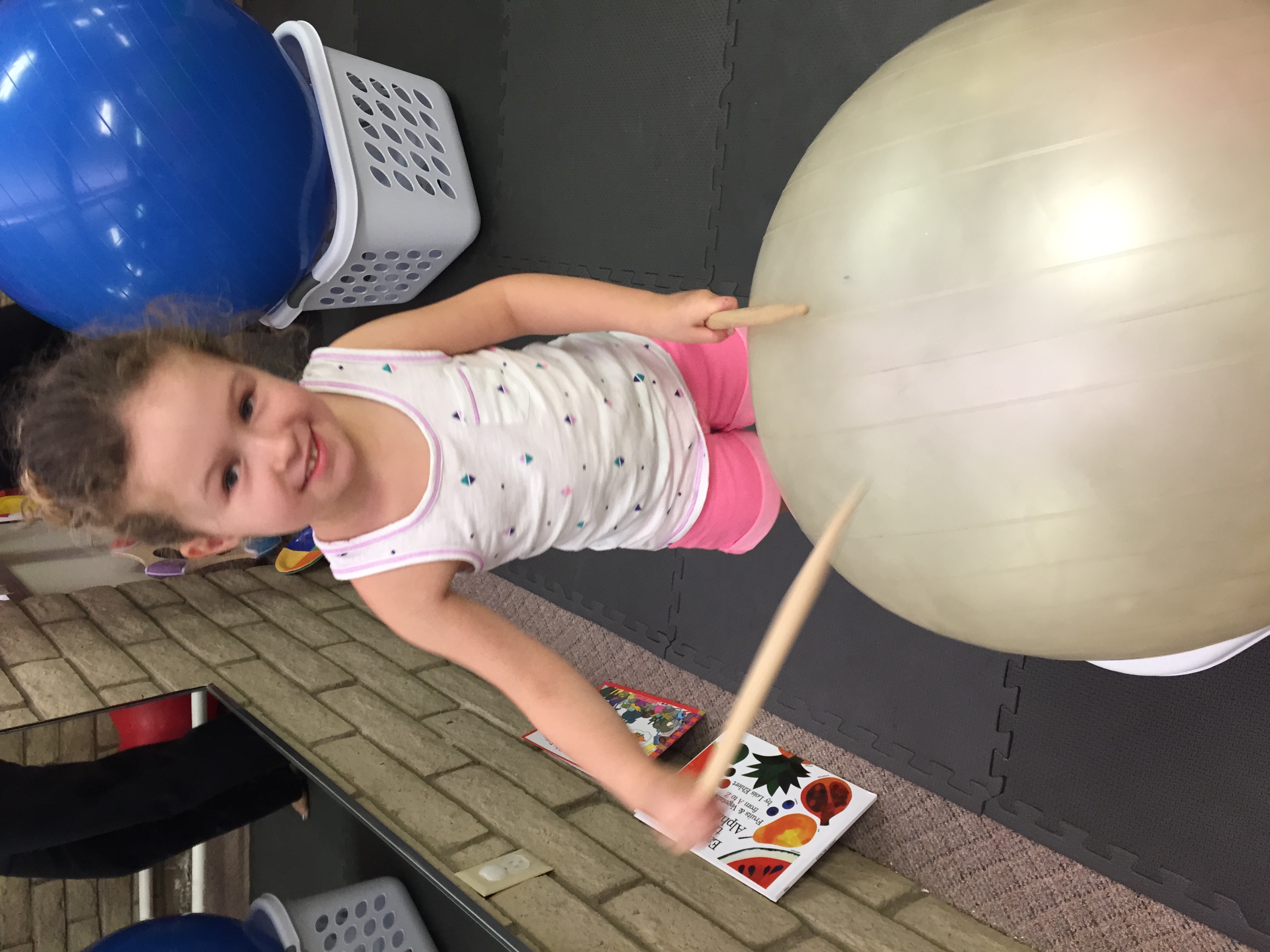 Little girl using drum sticks on yoga ball