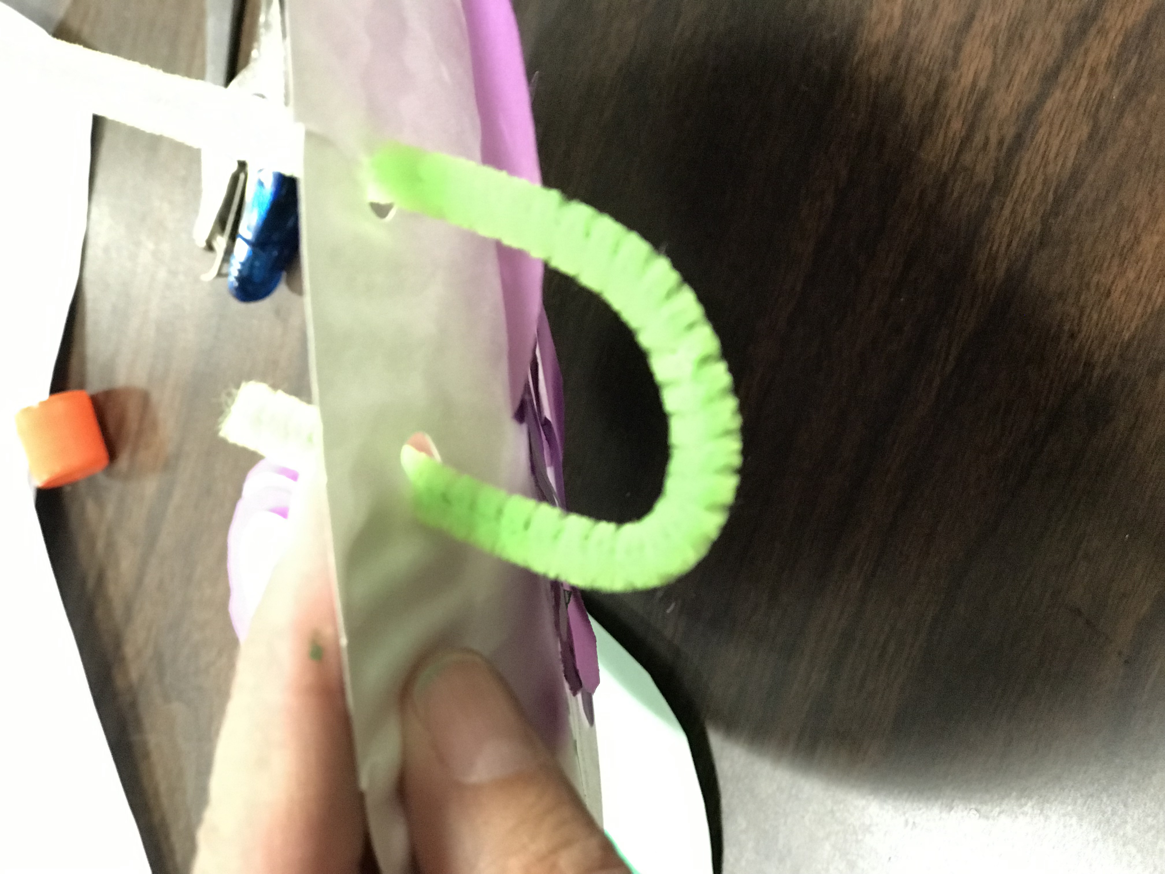 Feeding pipe cleaner stem through hole punched paper plate