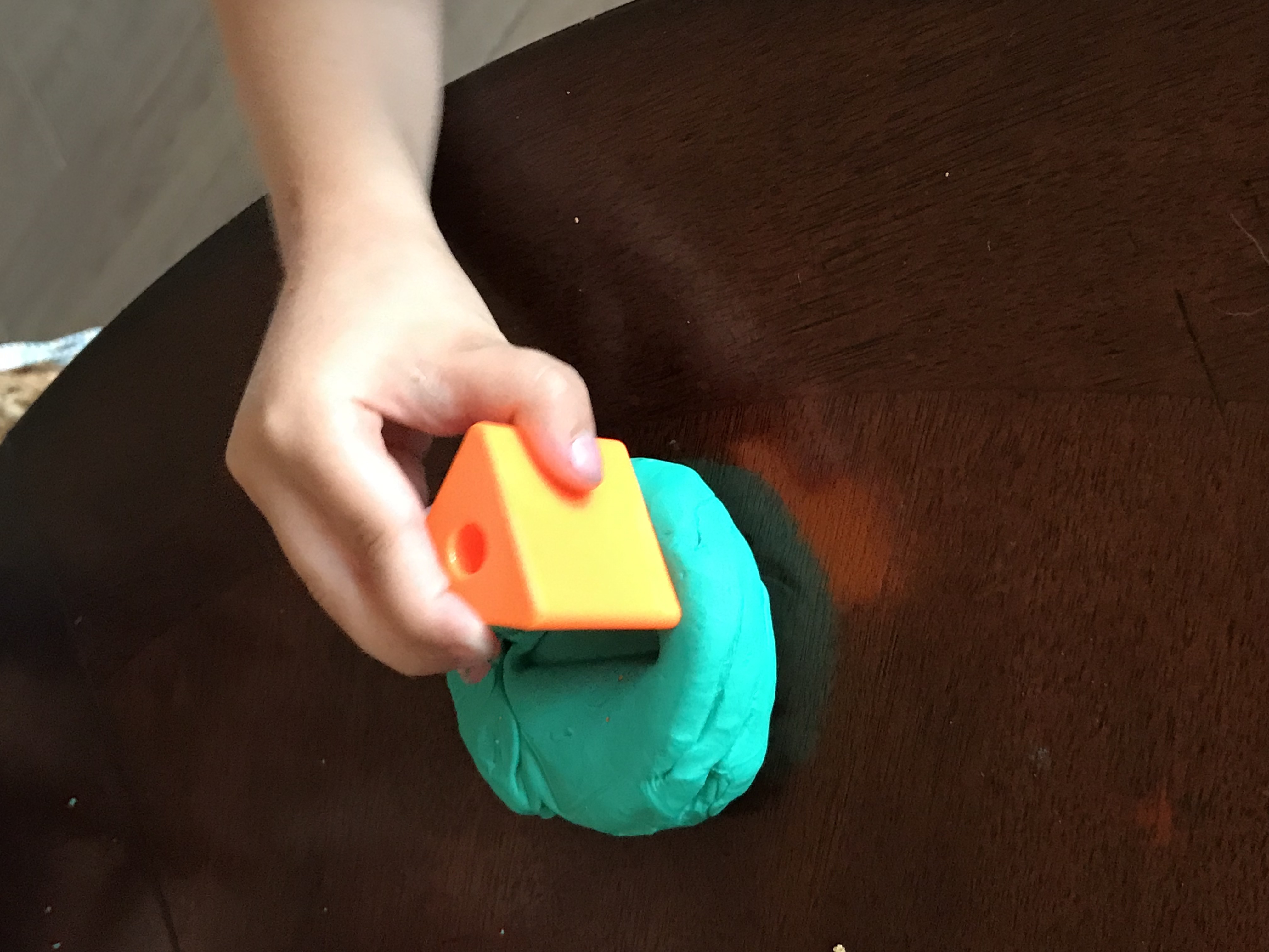 Pressing shape toy into Play Doh
