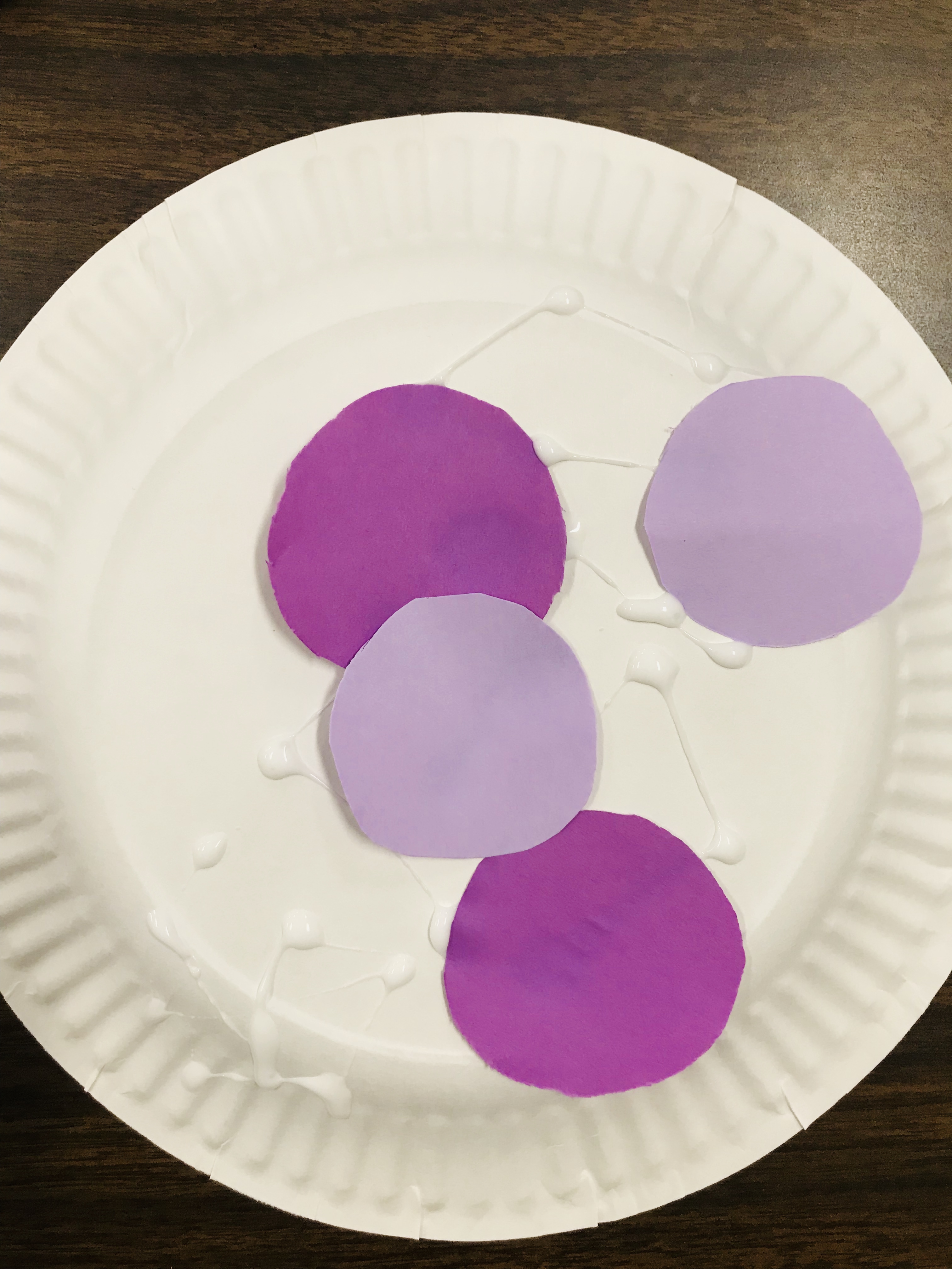 Gluing purple circles on paper plate